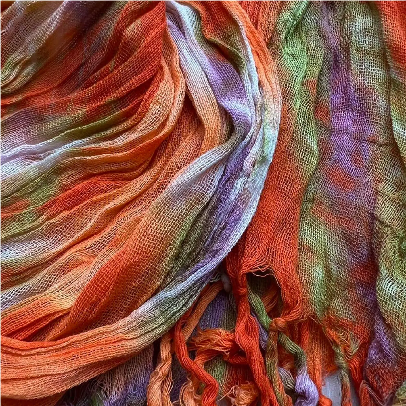 A vibrant loosely woven lightweight viscose scarf with orange green purple and white tie dye print for dress accessory