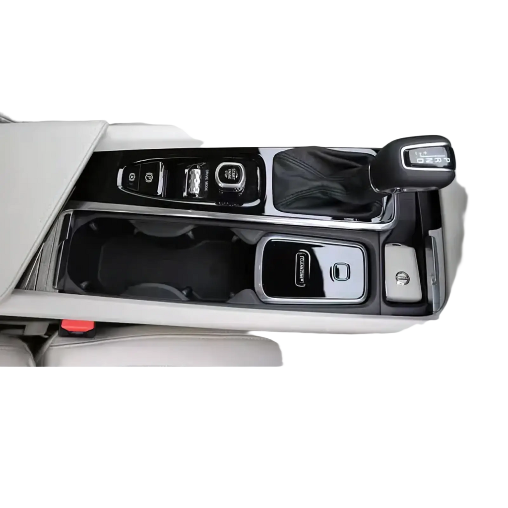 Black and silver glossy center console trim with integrated cup holders gear shift knob and button controls for volvo cleanzone wireless car charger and air purifier