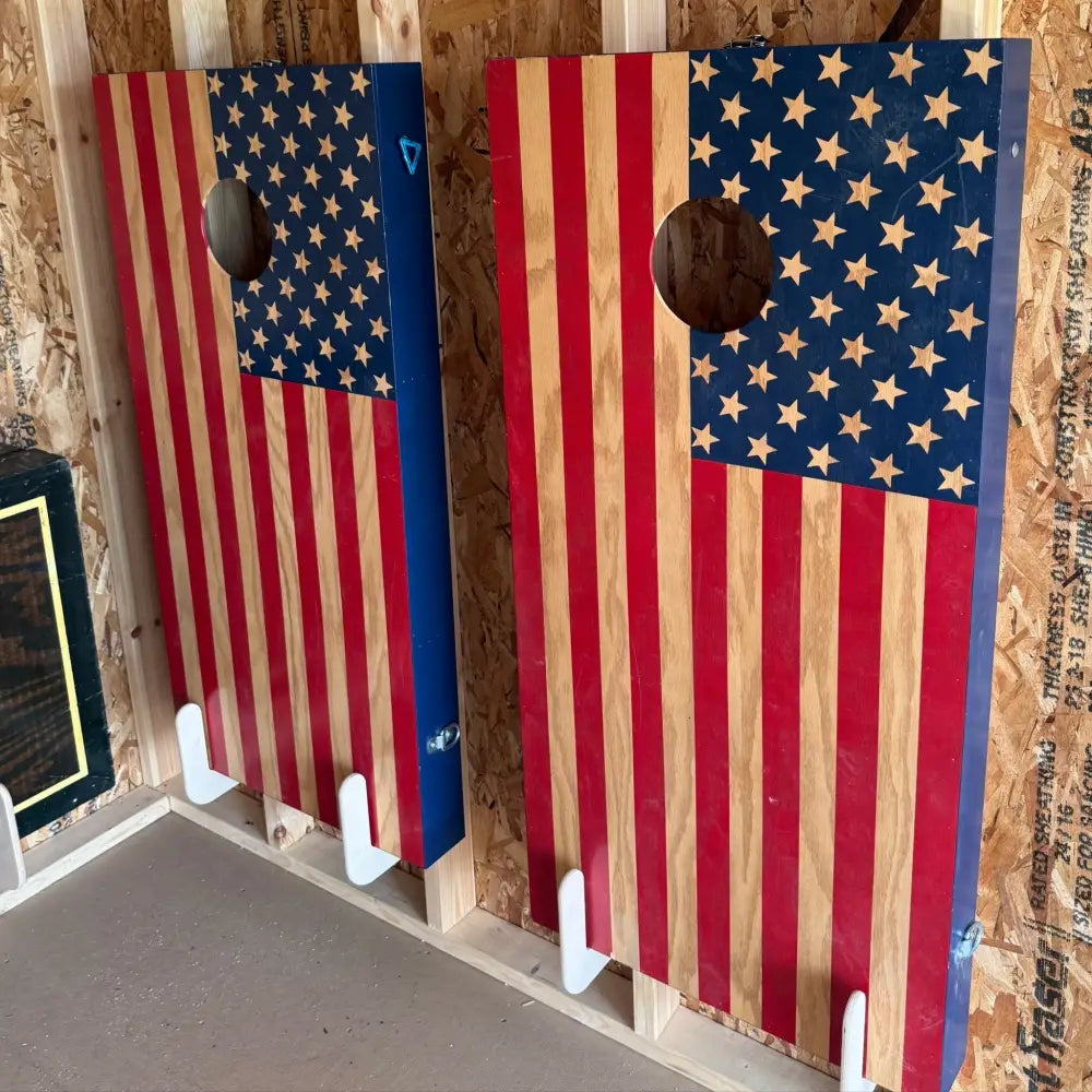 Birch plywood wall mounted cornhole board storage brackets holding american flag themed red white and blue cornhole boards