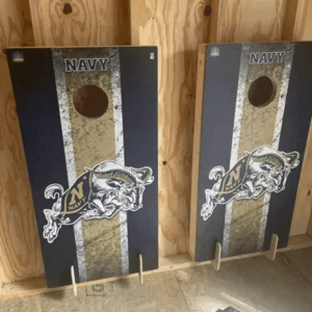 Birch plywood wall mounted cornhole board storage brackets holding navy themed cornhole boards with blue gold distressed mascot design