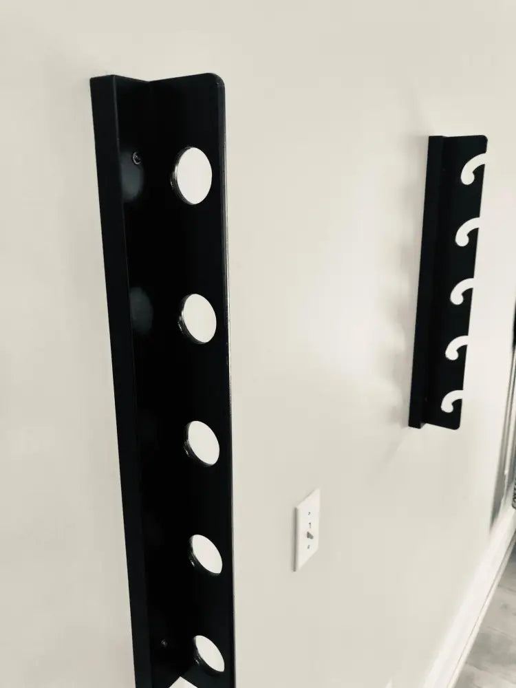 Black metal wall-mounted golf club rack with circular slots designed for organized club storage and display