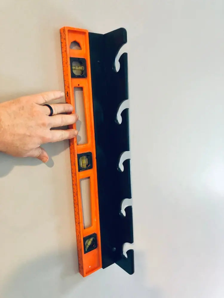 Orange and black birch wall-mounted fishing rod rack with curved cutouts for secure storage by Wisa