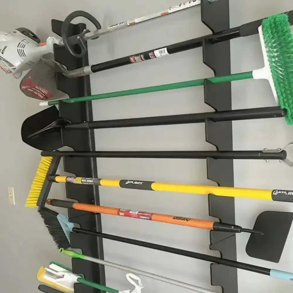 Black metal wall mounted garden tool and shovel rack holding various garden and cleaning tools by Lancaster Wooden