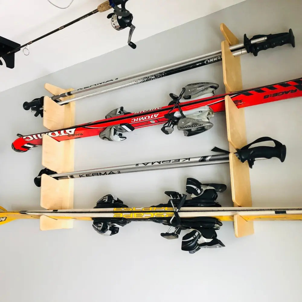 Birch plywood wall mounted four pair ski and pole rack holding red and black atomic skis with silver bindings