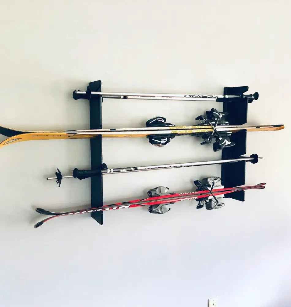 Black wall-mounted birch plywood ski and pole rack holding three pairs of skis and poles for organized storage