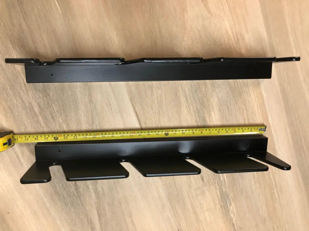 Black metal wall-mounted shoe rack with three slots and mounting brackets designed for organized storage