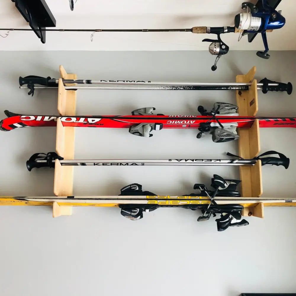 Red and black atomic ski poles with silver accents mounted on a birch plywood wall mounted four pair ski and pole rack