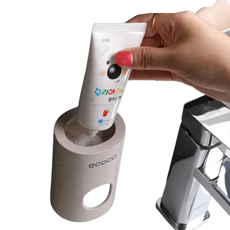 White wall mounted toothpaste dispenser and holder set with a strawberry flavored cartoon-themed toothpaste tube in beige holder