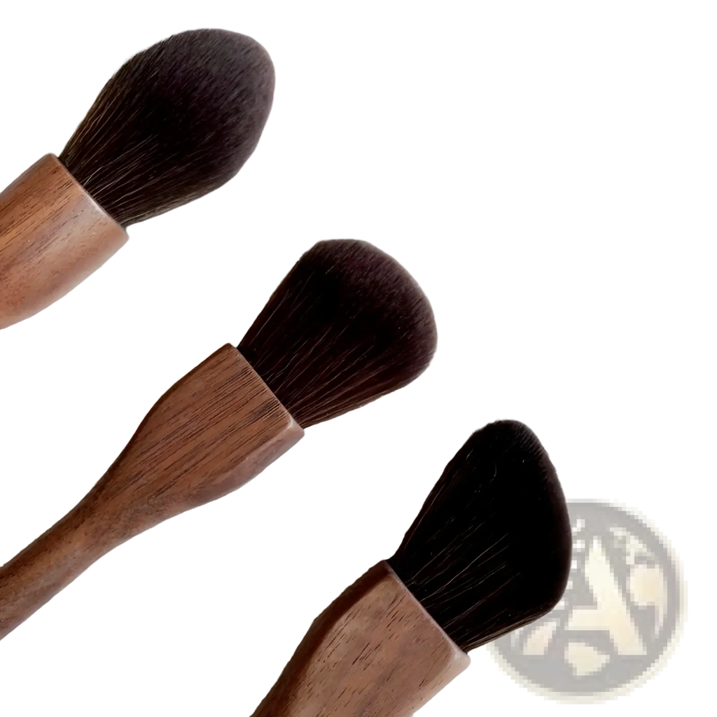 Three walnut wood makeup brushes with soft dense dark brown fiber bristles on a textured silver surface