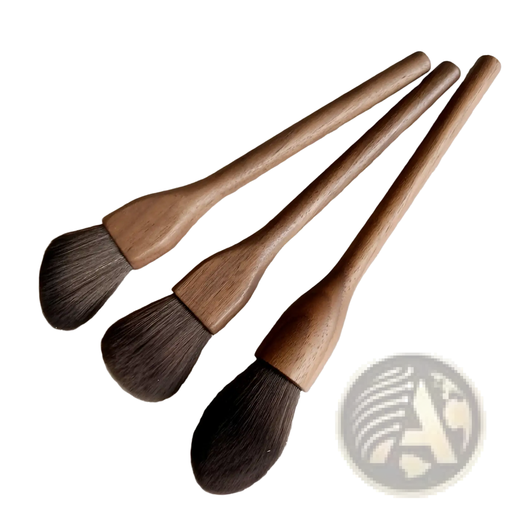Three wooden-handled walnut wood makeup brushes with soft dark brown fiber bristles arranged diagonally on textured surface