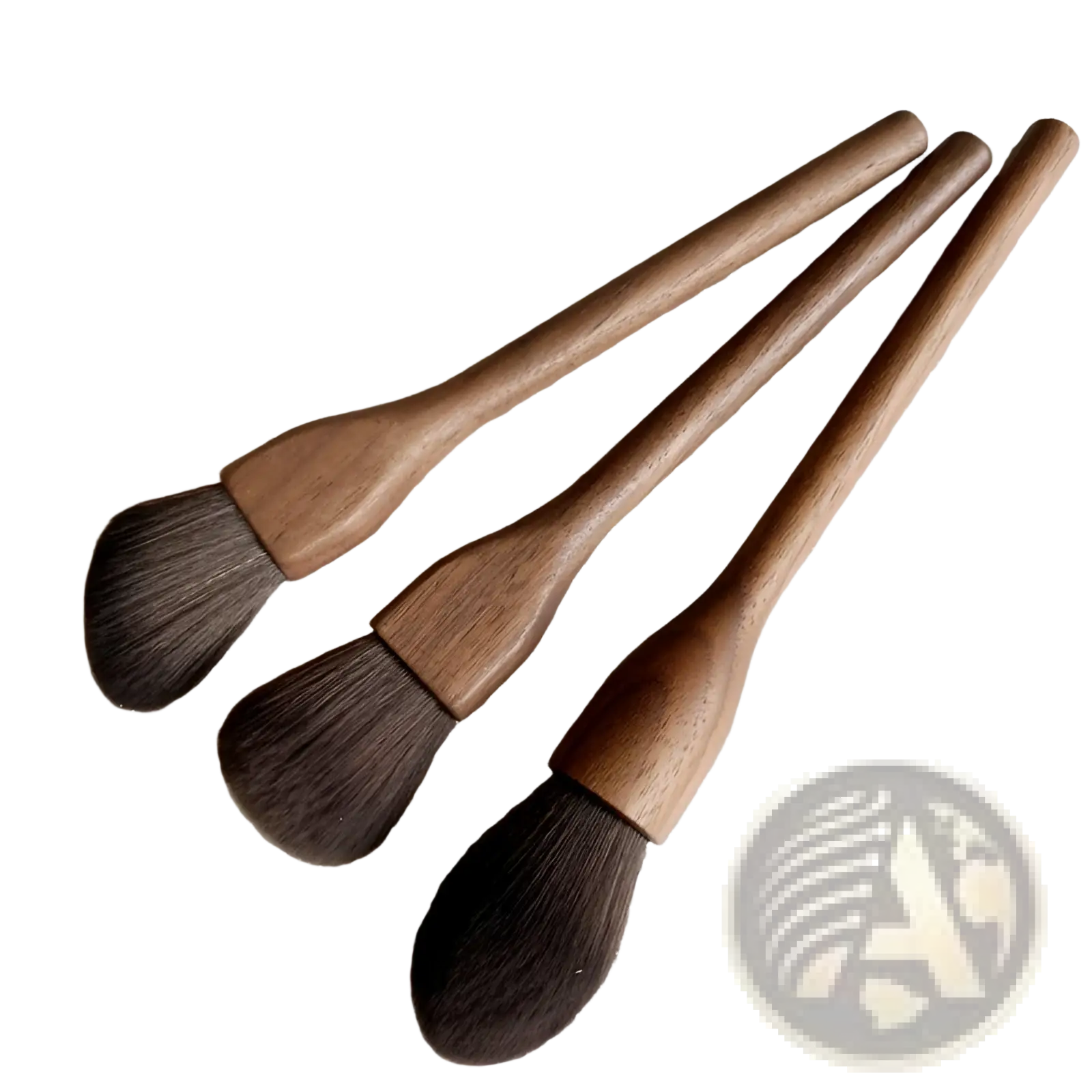 Three wooden-handled walnut wood makeup brushes with soft dark brown fiber bristles arranged diagonally on textured surface