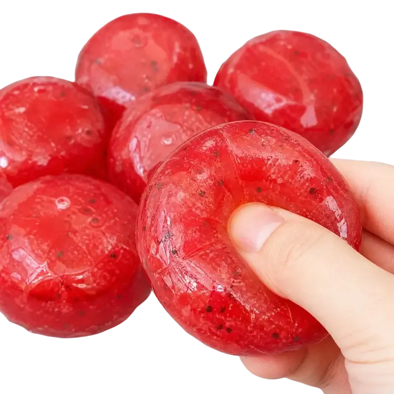 A translucent red strawberry-shaped squishy stress relief toy with black specks and a glossy textured surface