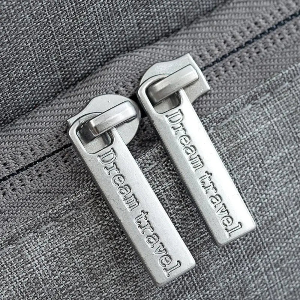 Silver metal zipper pulls engraved with dream travel on gray fabric of waterproof dream travel shoe bag with reinforced handles