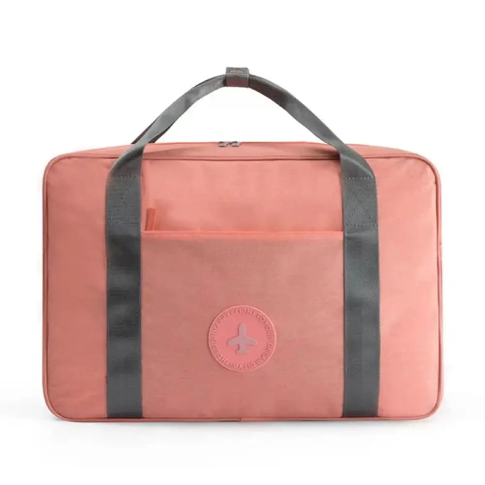A coral-colored waterproof dream travel shoe bag with gray fabric reinforced handles and a circular front logo patch