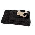 Black quilted waterproof pet bed mat and furniture protector with plush black and white dog toy resting on it