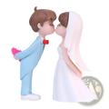 Cute resin wedding cake topper figurines of a bride in white gown and groom in light blue suit holding a pink heart