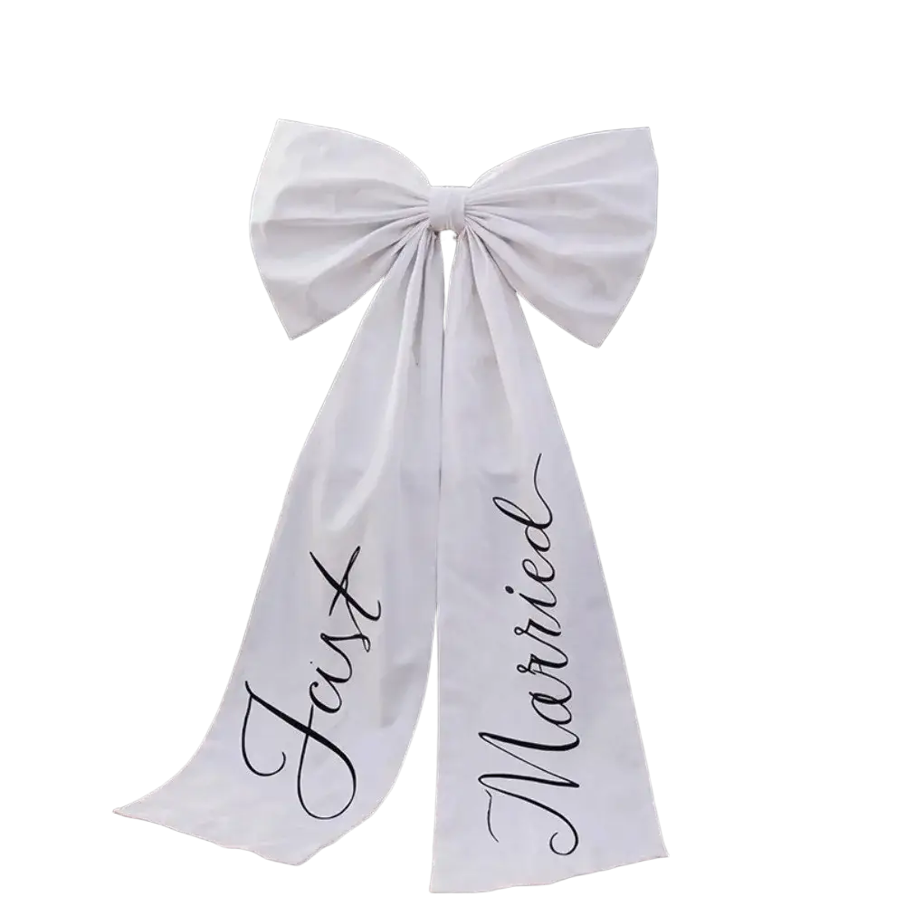 Large white satin wedding car bow with just married scripted in black cursive tied to the rear of a classic car