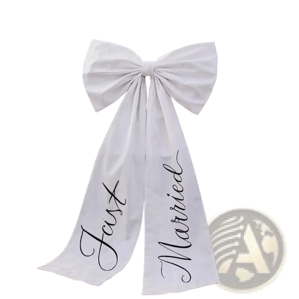 Large white satin wedding car bow with just married scripted in black cursive tied to the rear of a classic car