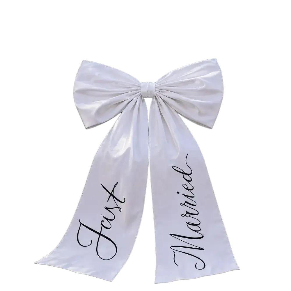Elegant large white satin wedding car bow with just married script in black cursive used as wedding day decor