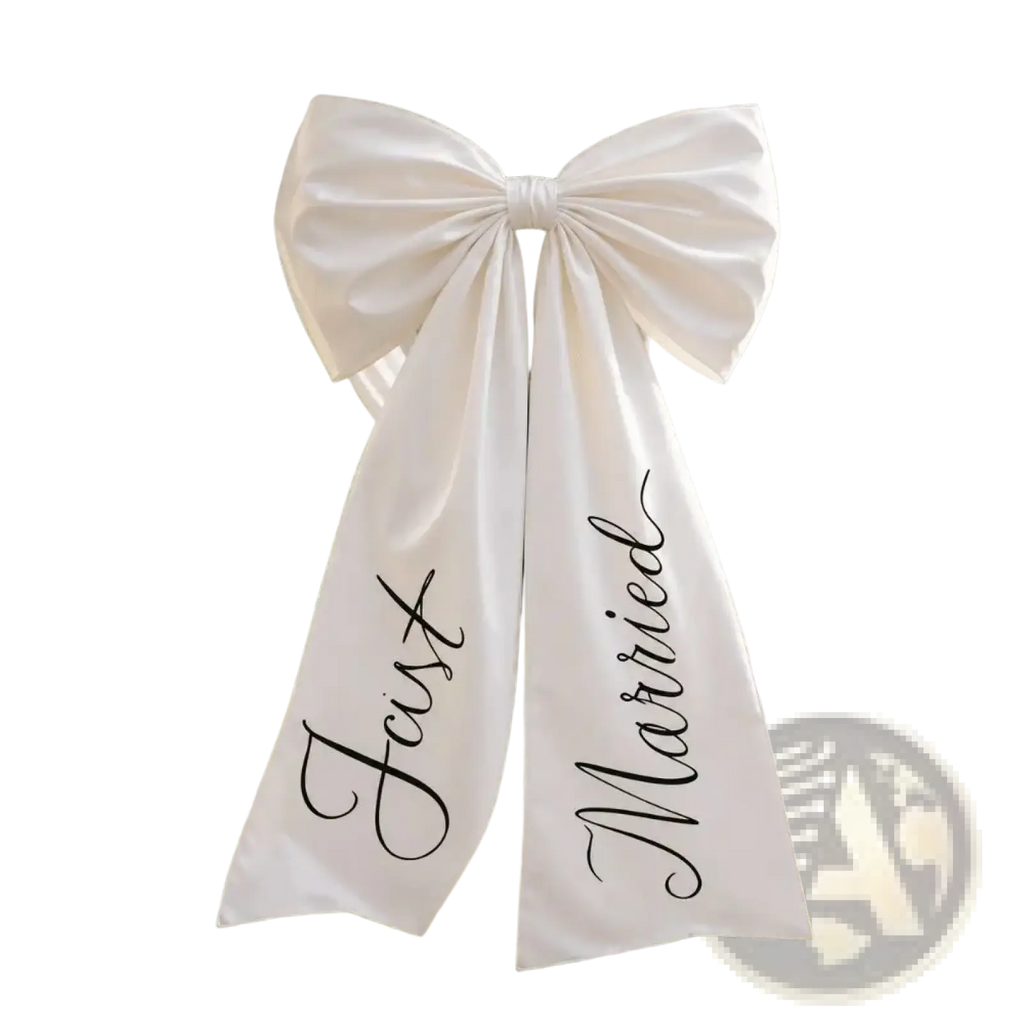 A white satin wedding car bow with a large bow and just married in elegant black cursive script