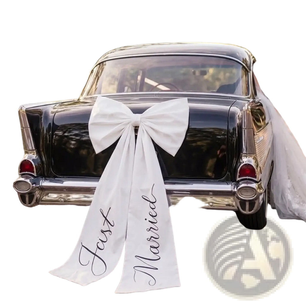 Large white satin wedding car bow with just married scripted in black cursive on the rear of a classic black car