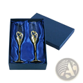 A pair of gold-finished wedding champagne flutes with intertwined heart designs in a blue satin gift box