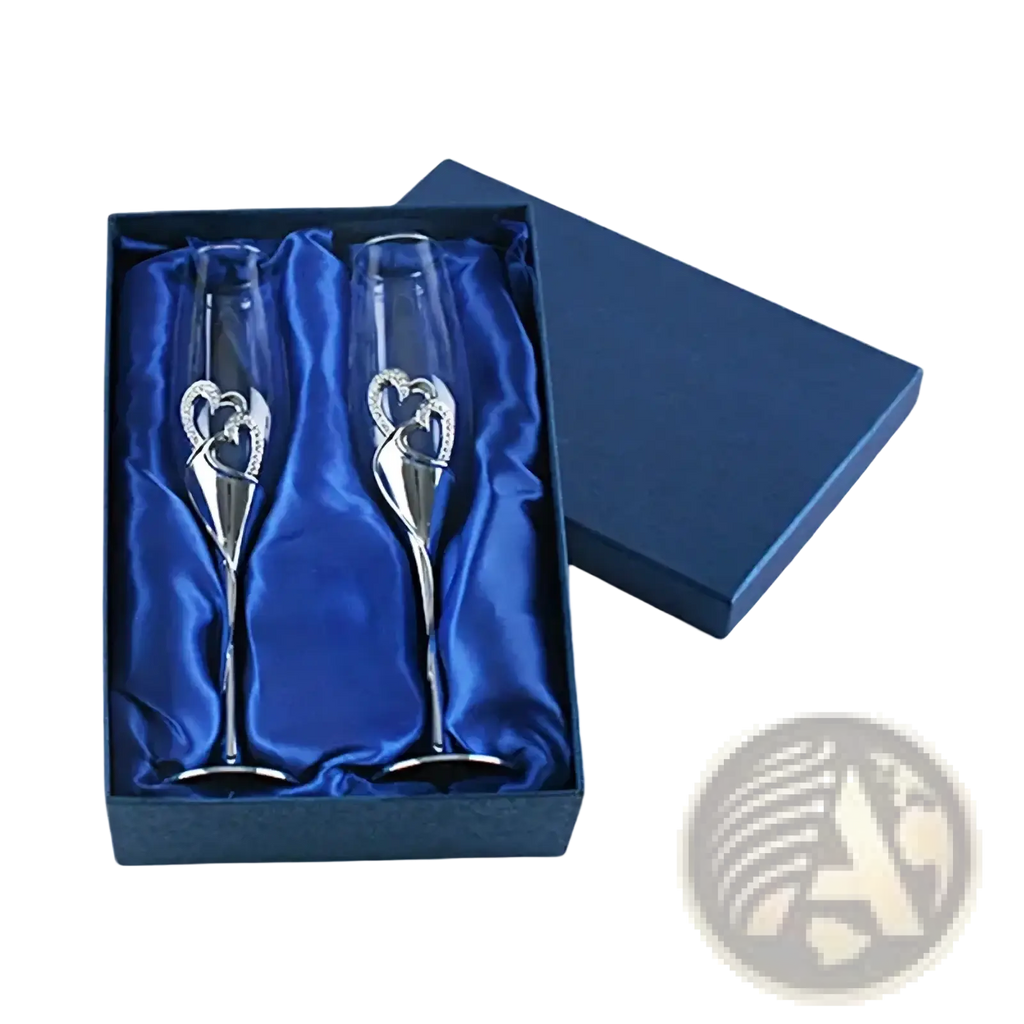 A pair of elegant silver champagne flutes with gold heart designs in a blue satin-lined wedding gift box