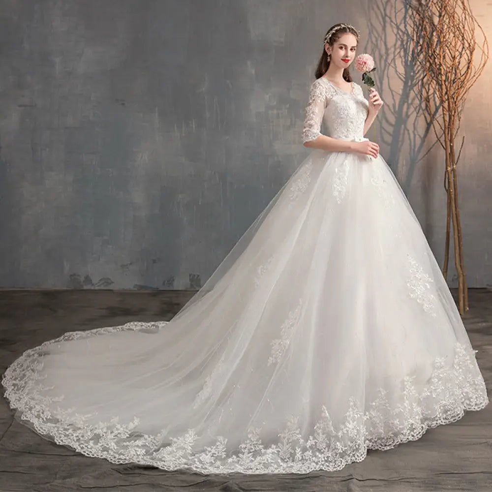 A flowing white lace v neck high waist wedding dress with intricate lace detailing and trailing sleeves
