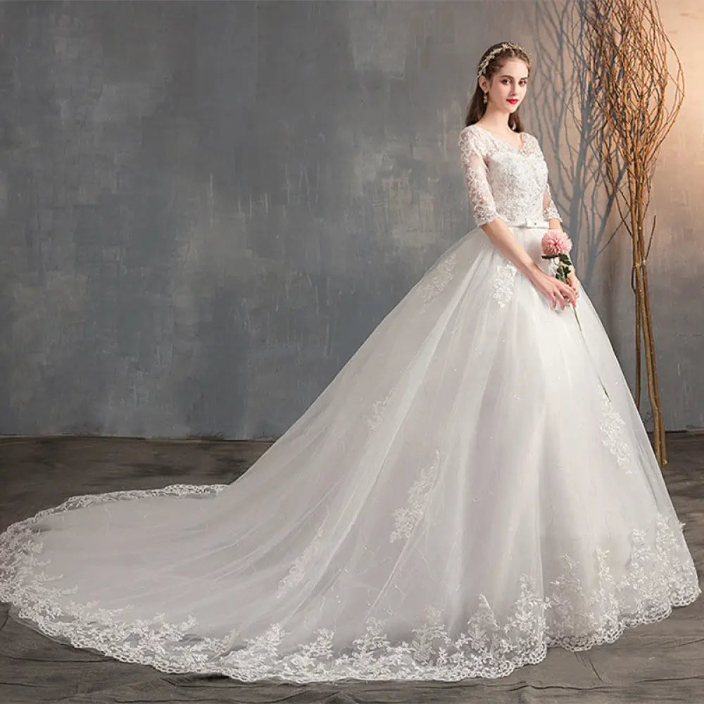 A white lace v neck high waist wedding dress with three quarter sleeves and floral embroidery along the hemline