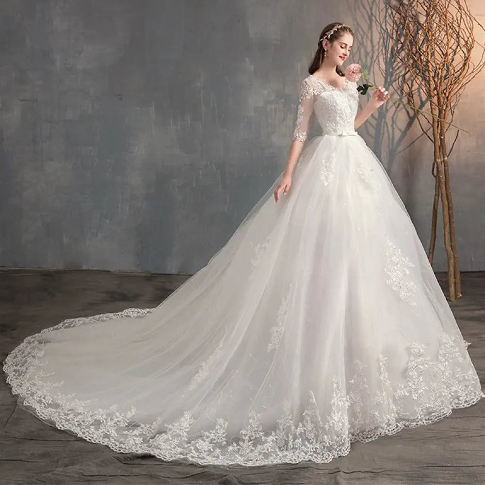 A flowing white lace v neck high waist wedding dress with intricate lace detailing and trailing sleeves