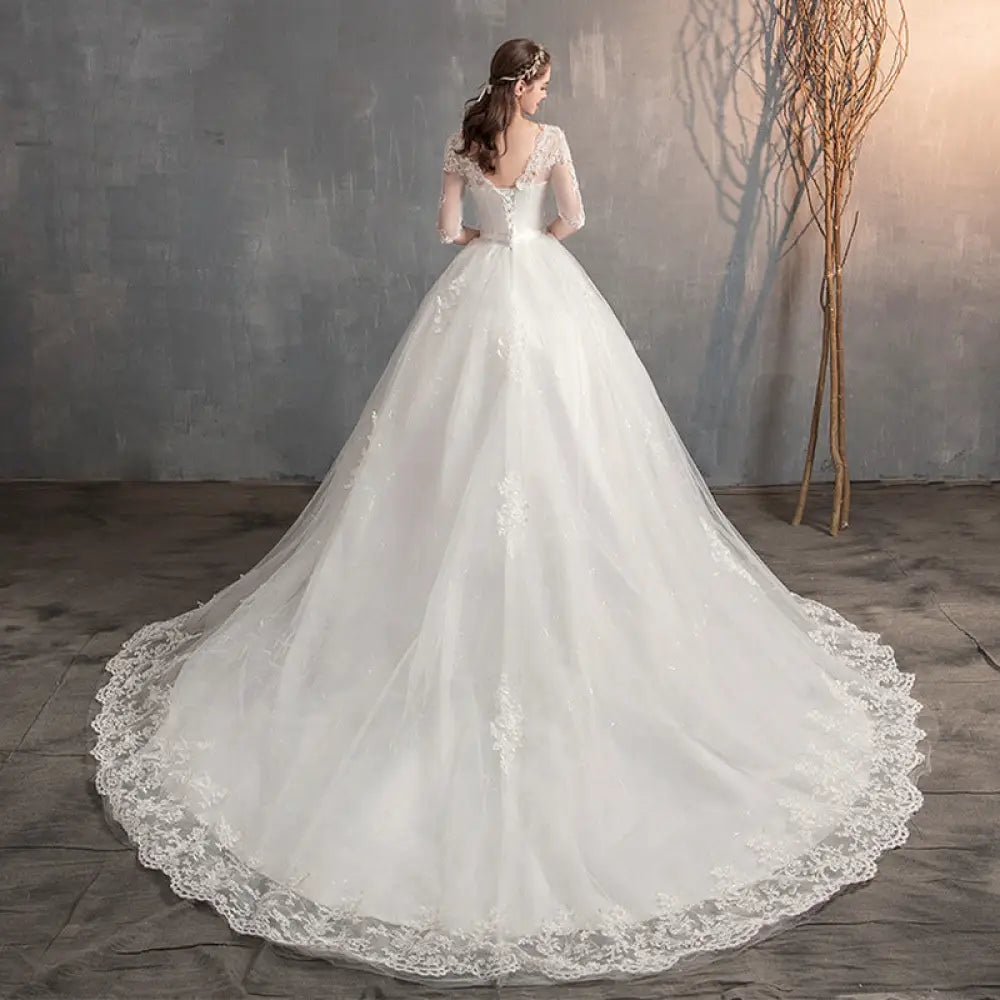 A flowing white lace v neck high waist wedding dress with delicate lace detailing and trailing sleeves