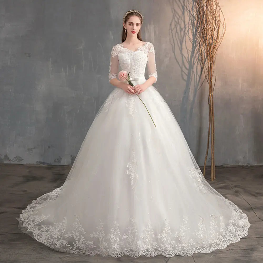 A white lace v neck high waist wedding dress with three quarter length trailing sleeves and a voluminous tulle skirt