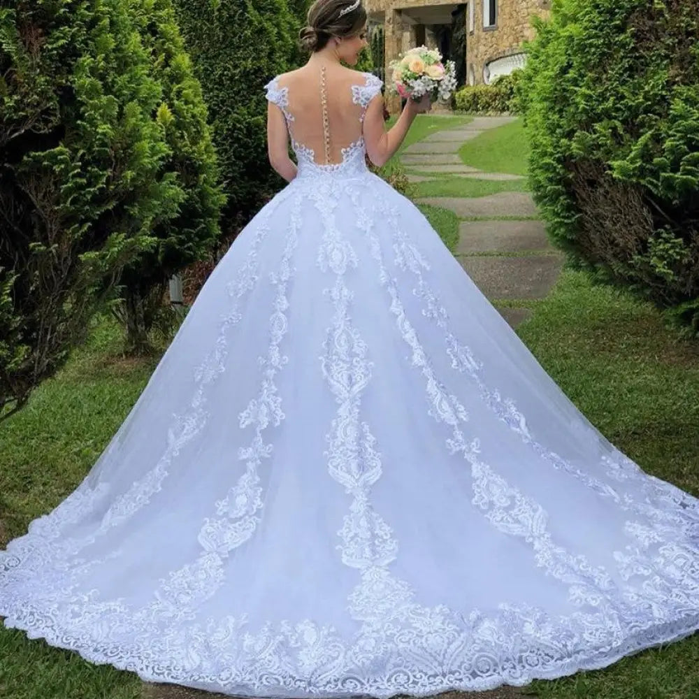 Back view of a vintage white lace off-the-shoulder wedding gown with a backless bodice and floral embroidered train