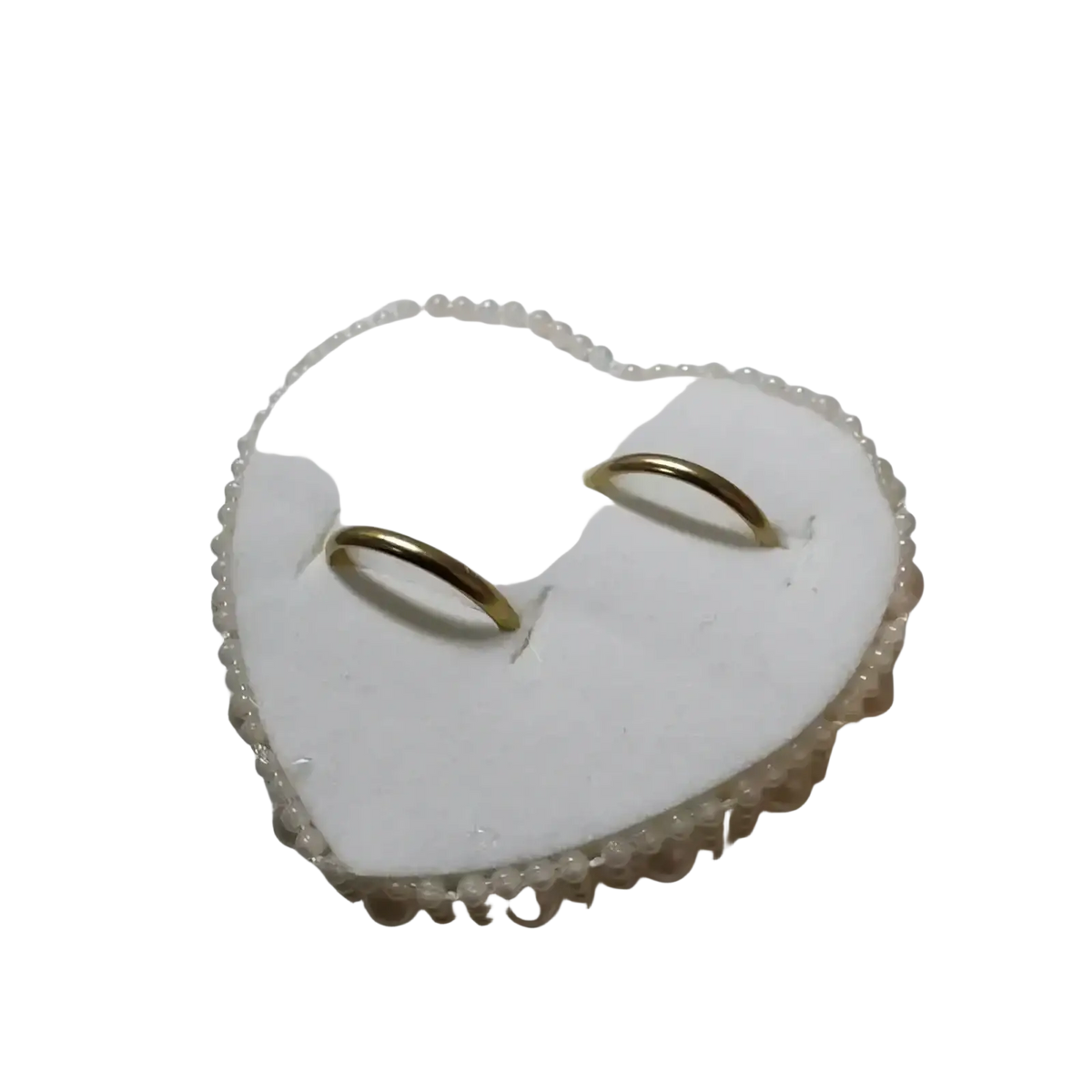 Heart wedding ring pillow in white satin with pearl trim and ribbon holding two gold wedding bands for ceremony