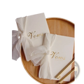 Cream-colored wedding vow book with gold foil lettering and a pearl-trimmed sheer ribbon bow in a vow books set