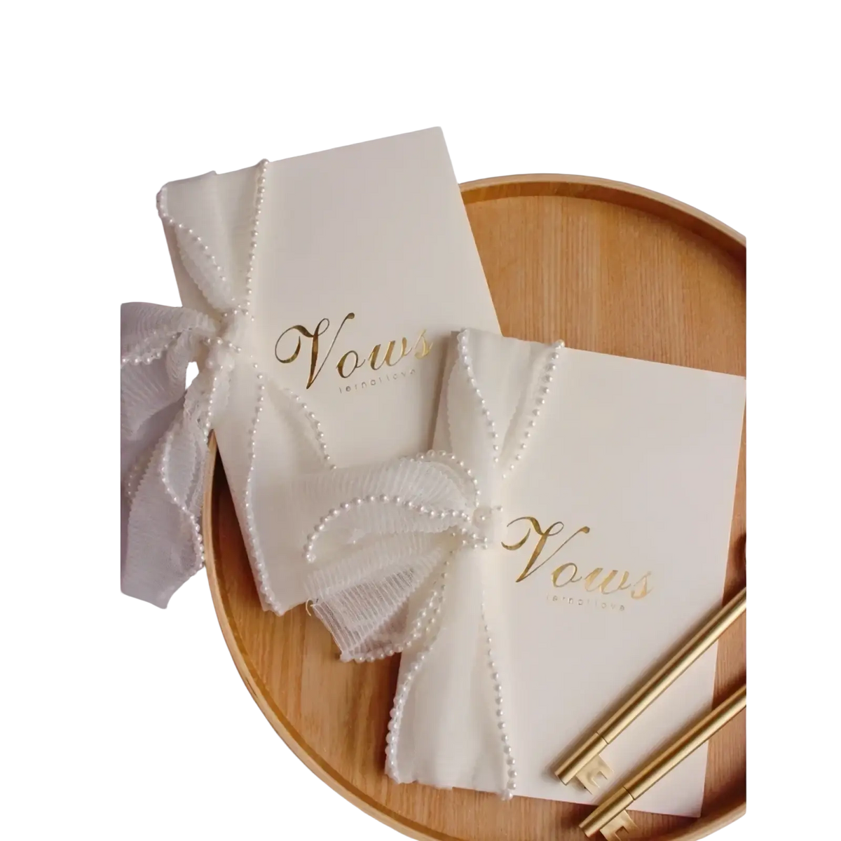Cream-colored wedding vow book with gold foil lettering and a pearl-trimmed sheer ribbon bow in a vow books set