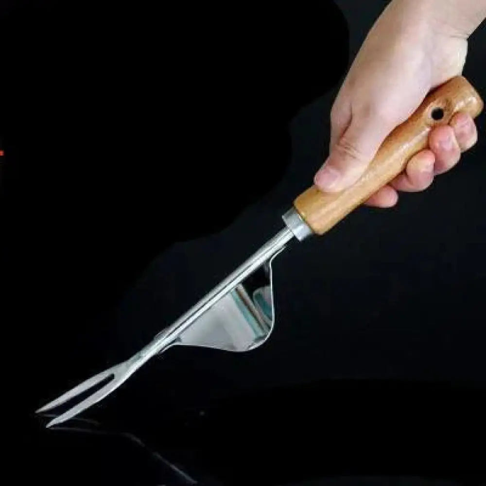 A hand grips an ergonomic garden fork with a light brown wooden handle and stainless steel tines for weeding