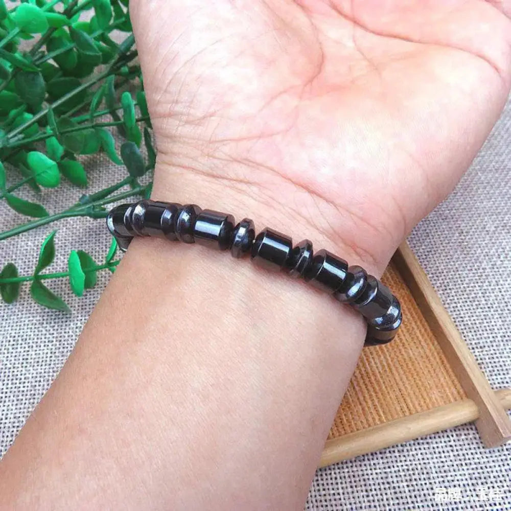 Black beaded pentagram stone magnetic hematite therapy bracelet with faceted glossy stones worn on wrist