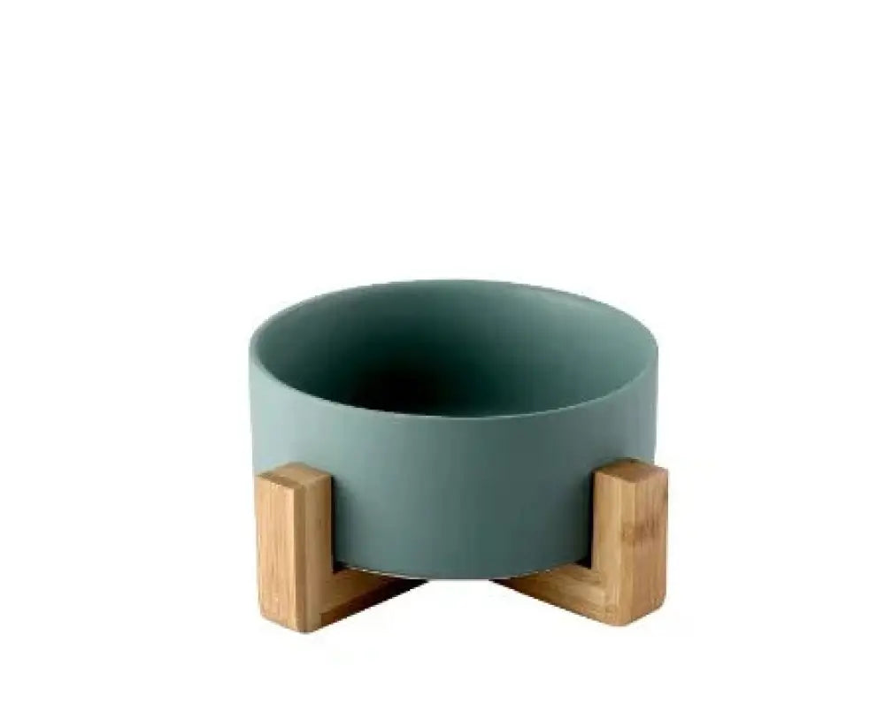 A minimalist matte teal ceramic bowl supported by two light wood l-shaped stands in a product set