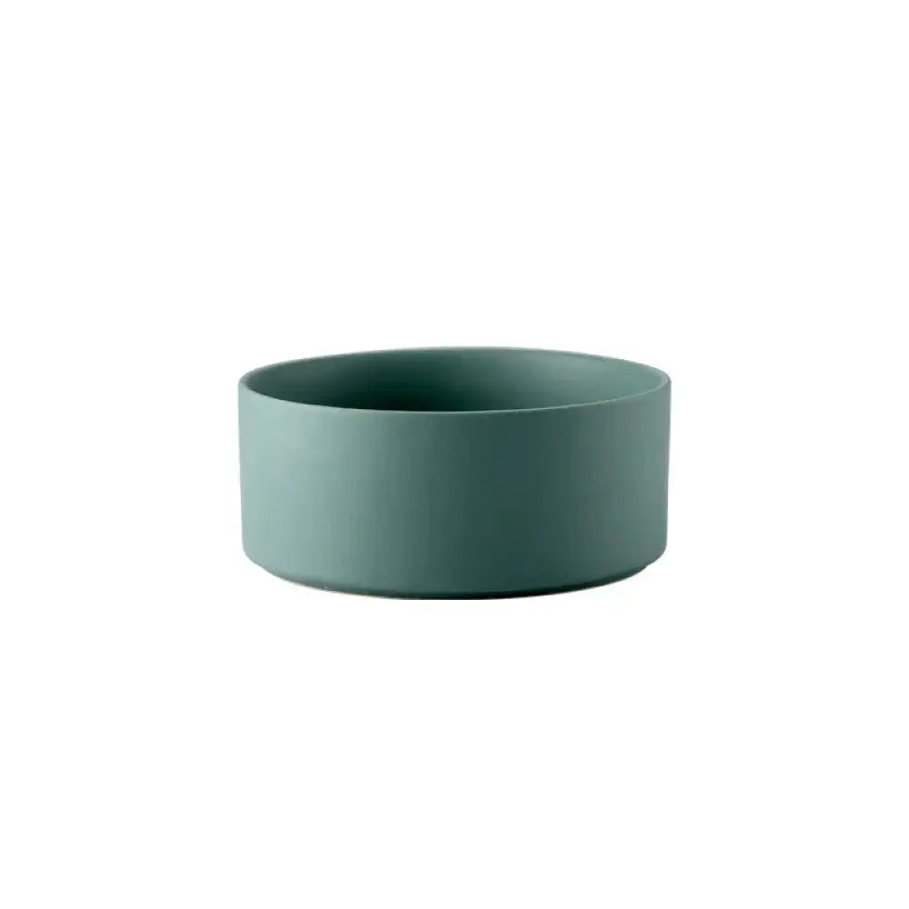 A sleek matte-finished teal ceramic bowl with clean minimalist lines from a minimalist matte ceramic bowl set with wooden stands