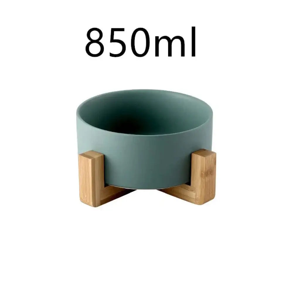 A minimalist matte teal ceramic bowl supported by three light wood legs from a ceramic bowl set