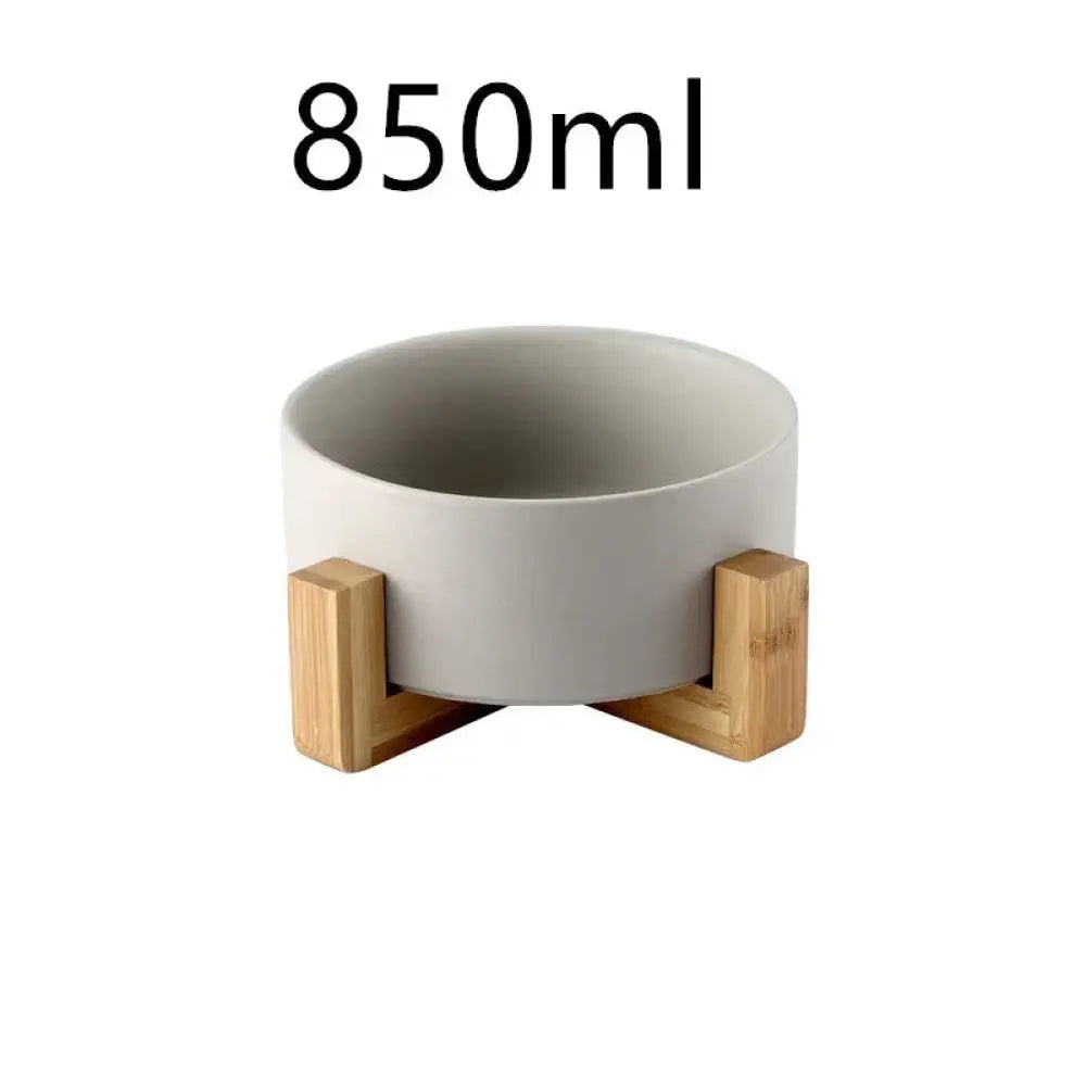 A sleek matte gray ceramic bowl with minimalist design supported by two light wood stands in a minimalist bowl set