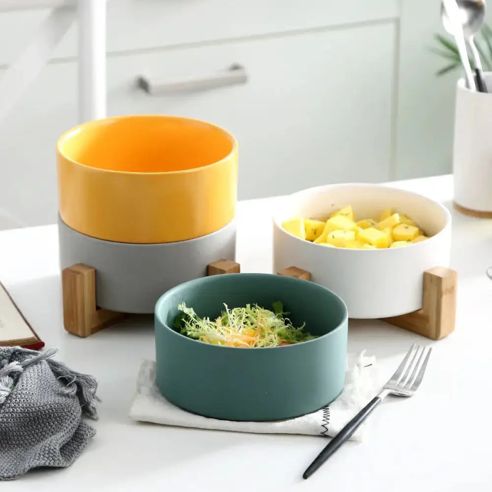 Set of three minimalist matte ceramic bowls with wooden stands in yellow white and teal colors for modern decor