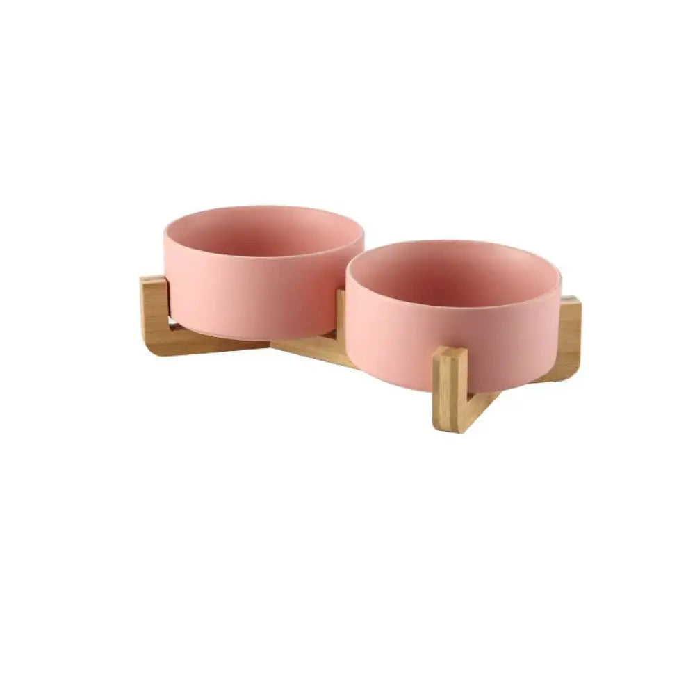 Minimalist matte ceramic bowl set with pink pet food and water bowls mounted on a light wood stand