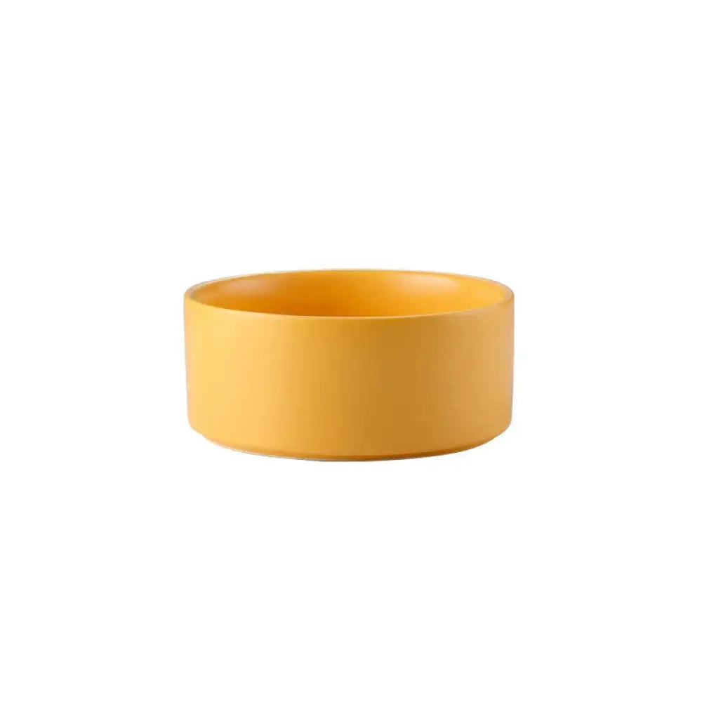 A sleek matte yellow ceramic bowl with a cylindrical shape and smooth edges from a minimalist ceramic bowl set