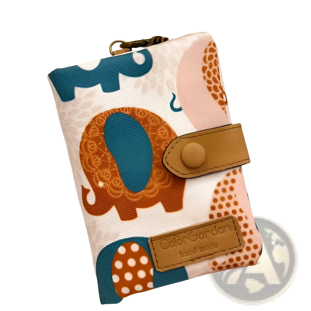 A white canvas tri fold multi card wallet with teal and orange elephant illustrations and a tan leather flap