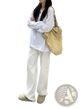 Beige canvas tote bag with a chain strap displayed alongside white high waist wide leg jeans