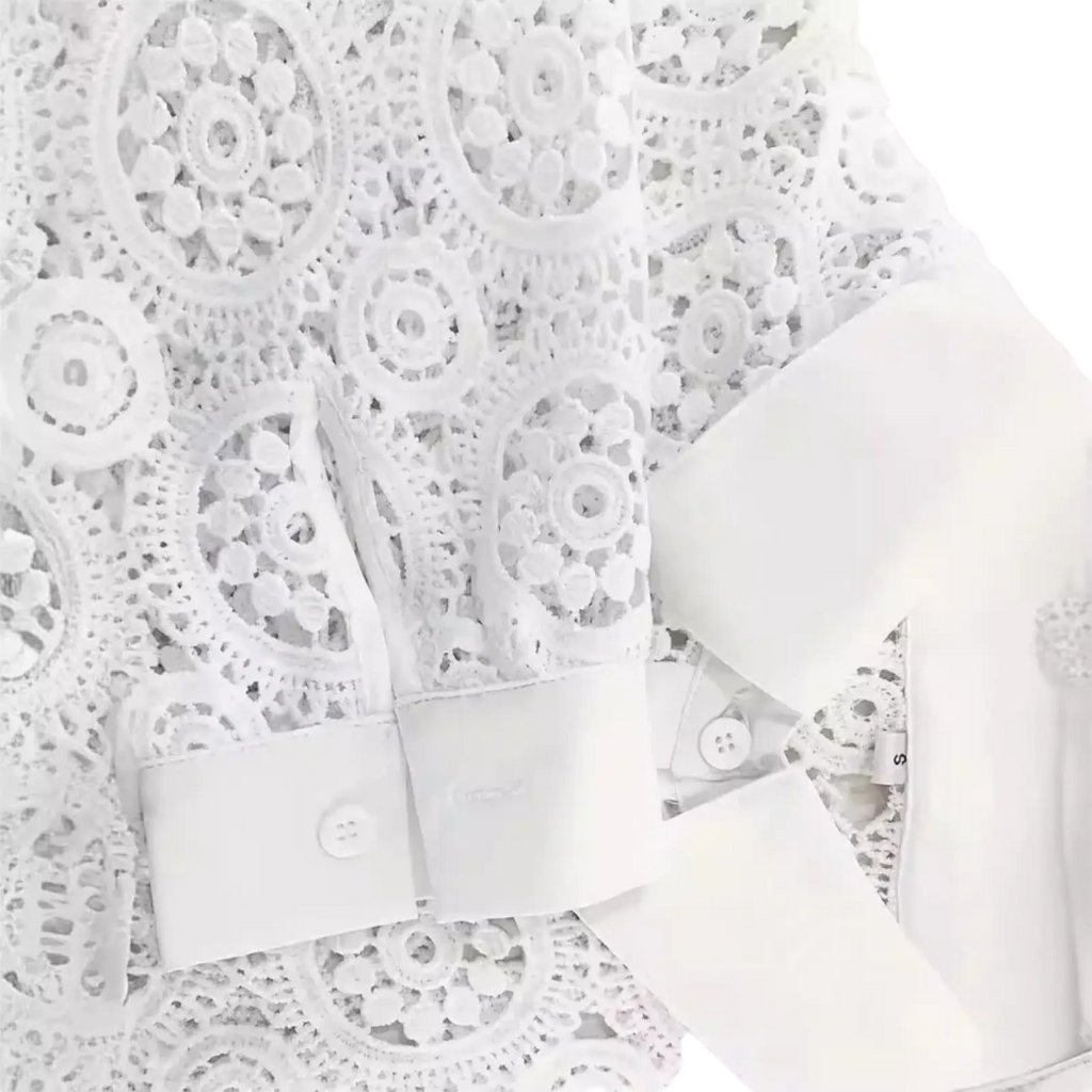 White lace office blouse featuring intricate circular patterns and satin cuffs in a classic white design