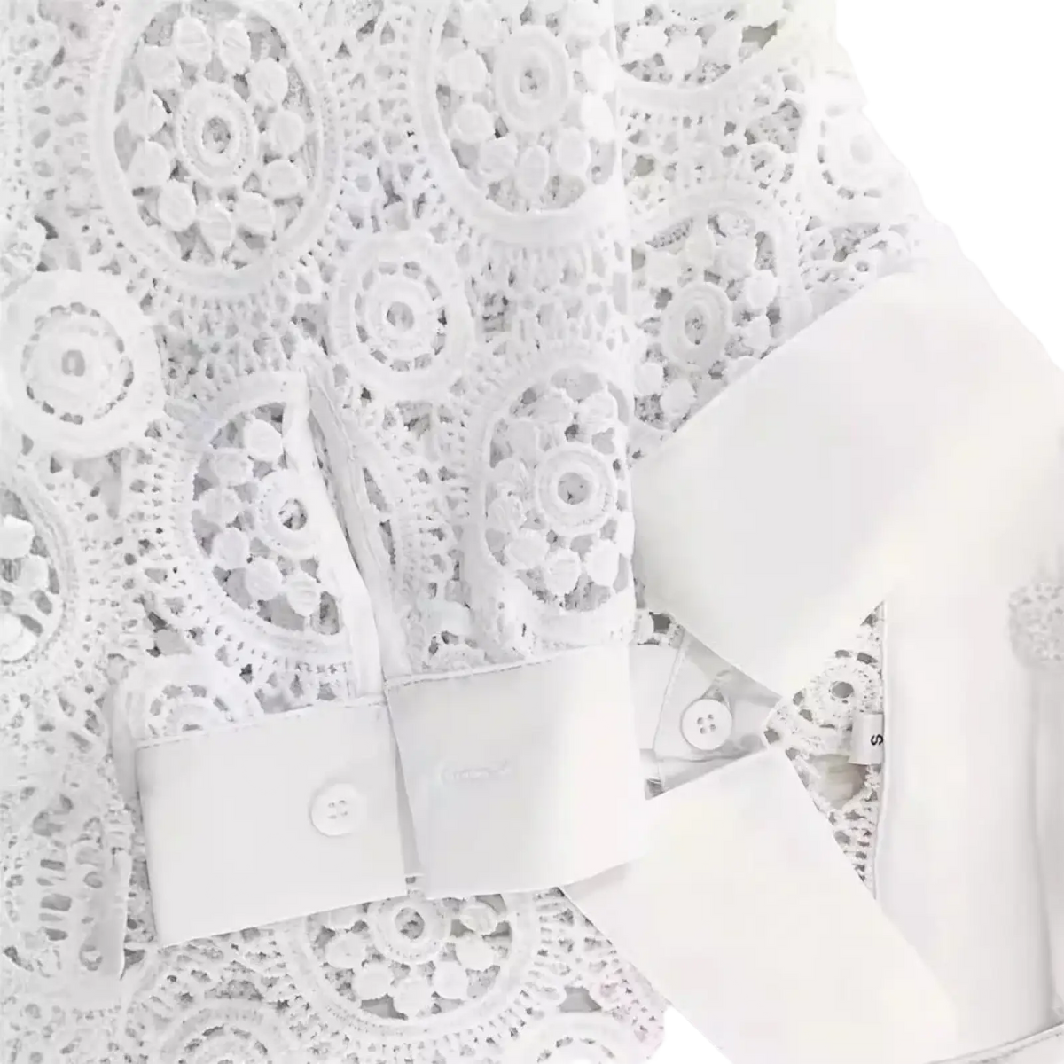 White lace office blouse featuring intricate circular patterns and satin cuffs in a classic white design