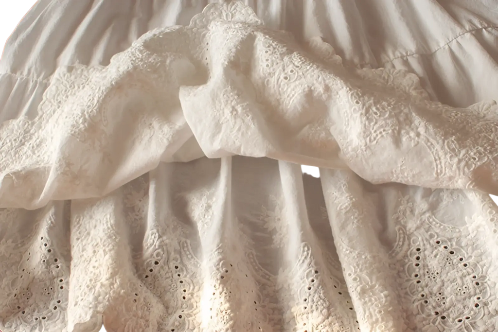 White lace tiered sundress with delicate eyelet embroidery and soft ruffled layers in a skirt design